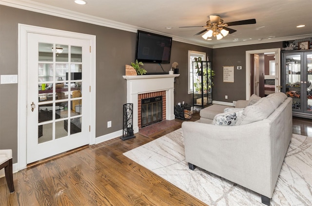 living room featuring baseboards, recessed lighting, a ceiling fan, a brick fireplace, and crown molding