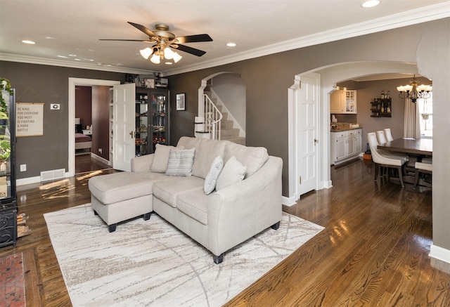 living room featuring ceiling fan with notable chandelier, visible vents, arched walkways, and ornamental molding