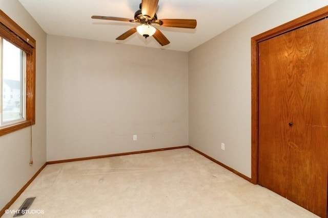 unfurnished bedroom with visible vents, baseboards, ceiling fan, light colored carpet, and a closet