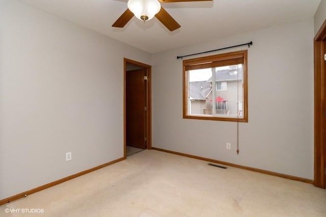 unfurnished room with visible vents, light colored carpet, baseboards, and ceiling fan