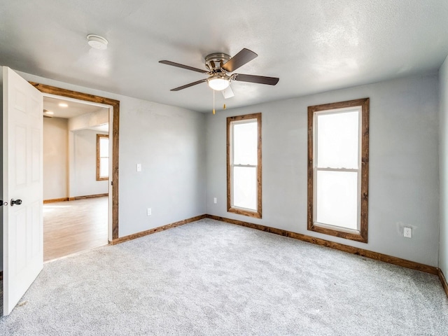 unfurnished room with baseboards, a ceiling fan, carpet flooring, and a textured ceiling