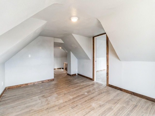 additional living space featuring vaulted ceiling, baseboards, and wood finished floors