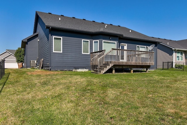 rear view of house featuring a yard, a wooden deck, and a shingled roof