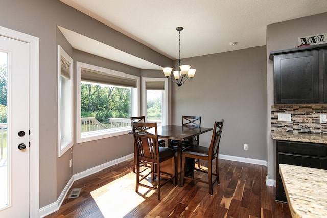 dining area with dark wood-style floors, visible vents, a notable chandelier, and baseboards