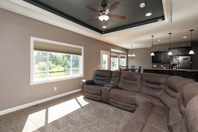 carpeted living area with visible vents, baseboards, recessed lighting, ceiling fan with notable chandelier, and a raised ceiling