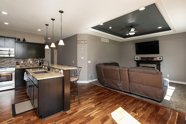 kitchen featuring visible vents, a sink, appliances with stainless steel finishes, a raised ceiling, and a kitchen breakfast bar