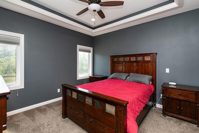 bedroom with a raised ceiling, carpet flooring, a ceiling fan, and baseboards