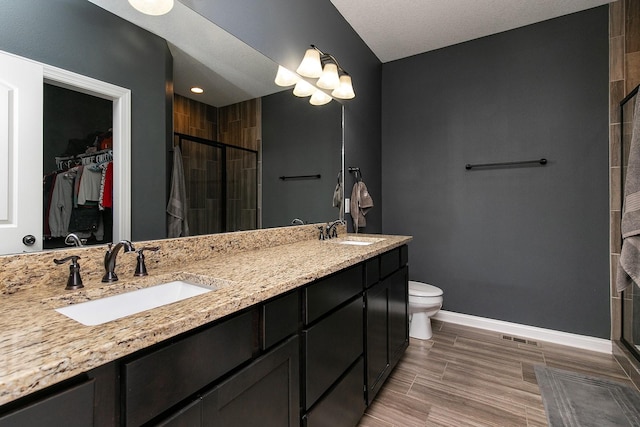 full bathroom with a walk in closet, a shower stall, baseboards, and a sink