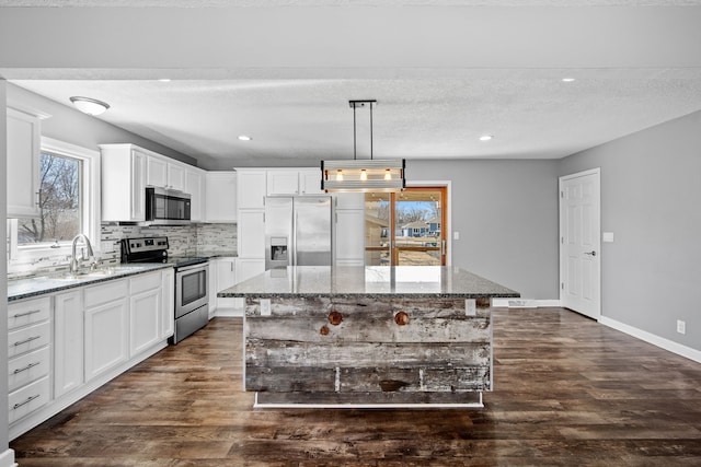 kitchen with stone counters, dark wood finished floors, appliances with stainless steel finishes, and a sink