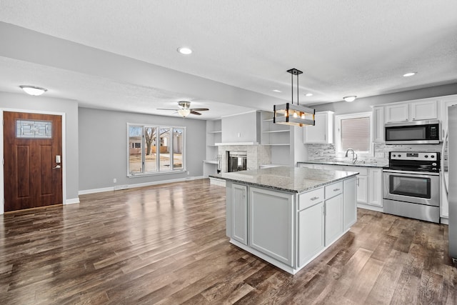 kitchen featuring dark wood-style floors, a kitchen island, stainless steel appliances, a textured ceiling, and white cabinetry