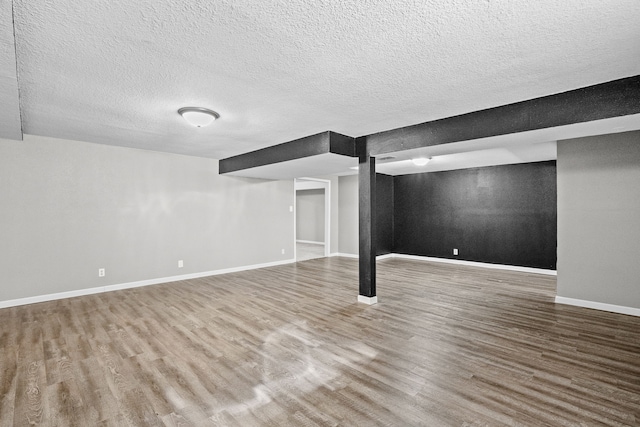 finished below grade area with wood finished floors, baseboards, and a textured ceiling