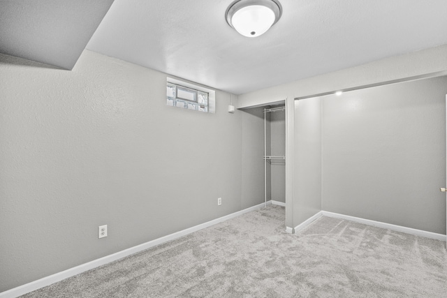 below grade area with baseboards, carpet flooring, and a textured wall