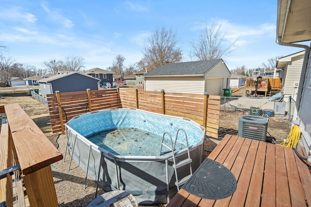 deck with an outbuilding, a jacuzzi, central AC, fence, and a residential view