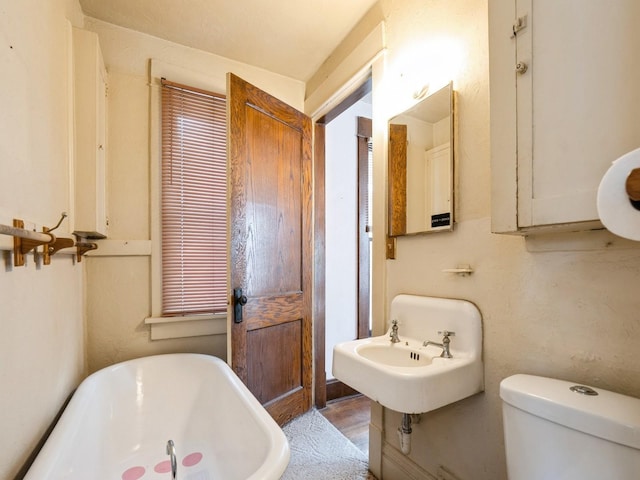 full bath featuring a sink, a freestanding tub, and toilet