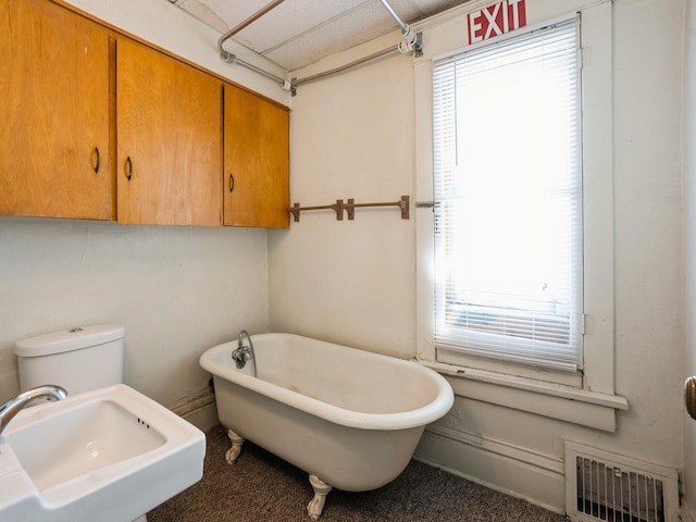 bathroom featuring a soaking tub, visible vents, toilet, and a sink