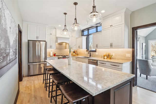 kitchen with white cabinetry, light wood-style floors, appliances with stainless steel finishes, and a sink