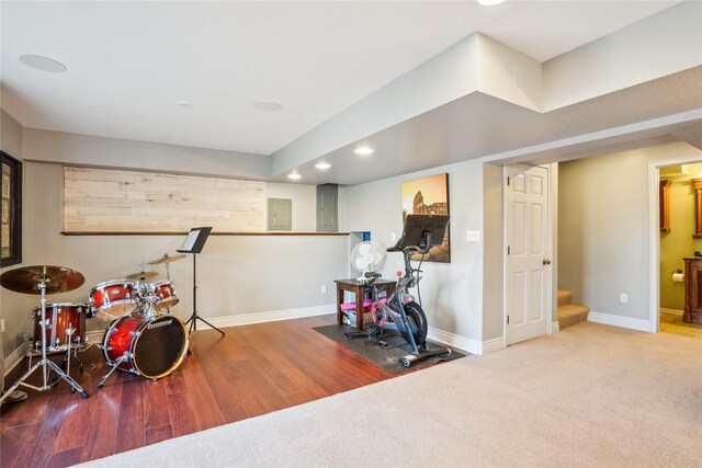 rec room featuring wood finished floors, baseboards, electric panel, recessed lighting, and carpet flooring