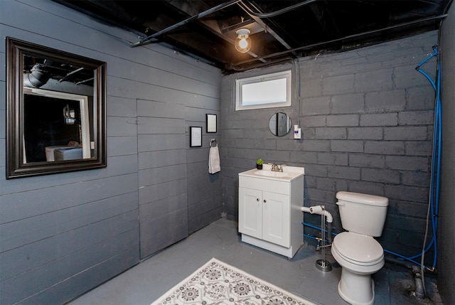 bathroom with vanity, toilet, and concrete floors