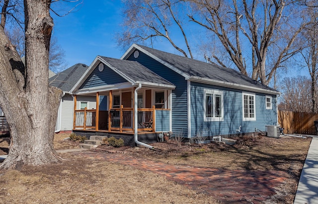 exterior space featuring covered porch, roof with shingles, central AC, and fence