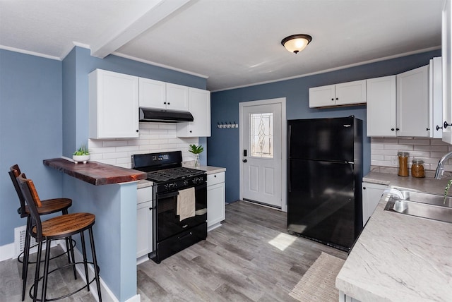 kitchen with light wood-type flooring, black appliances, under cabinet range hood, a sink, and crown molding