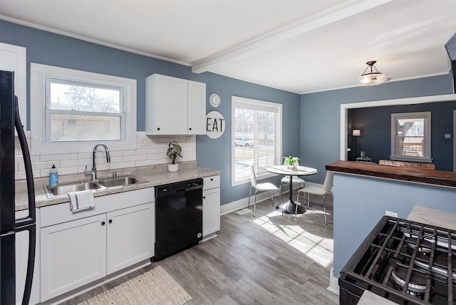 kitchen with light wood-type flooring, a sink, backsplash, black dishwasher, and white cabinets