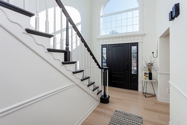 entryway with baseboards, a high ceiling, and light wood finished floors