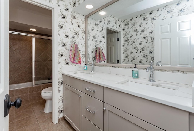 bathroom with a sink, toilet, and wallpapered walls