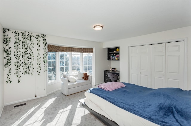 bedroom with light carpet, visible vents, a closet, and baseboards