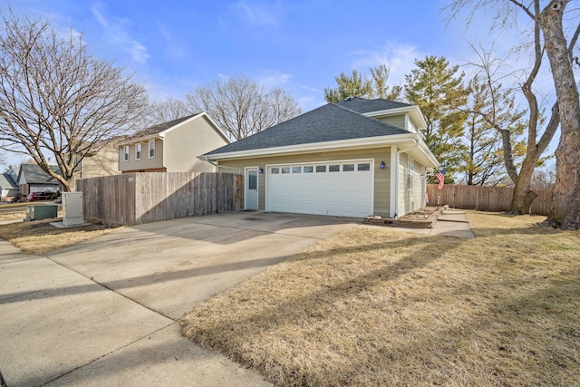 view of home's exterior with concrete driveway, an attached garage, fence, and roof with shingles