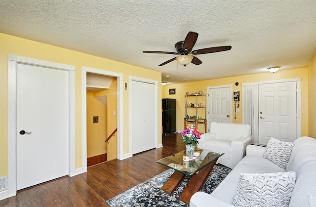 living room featuring dark wood finished floors, ceiling fan, a textured ceiling, and baseboards