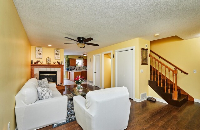 living area featuring dark wood-style floors, stairway, a tiled fireplace, and baseboards