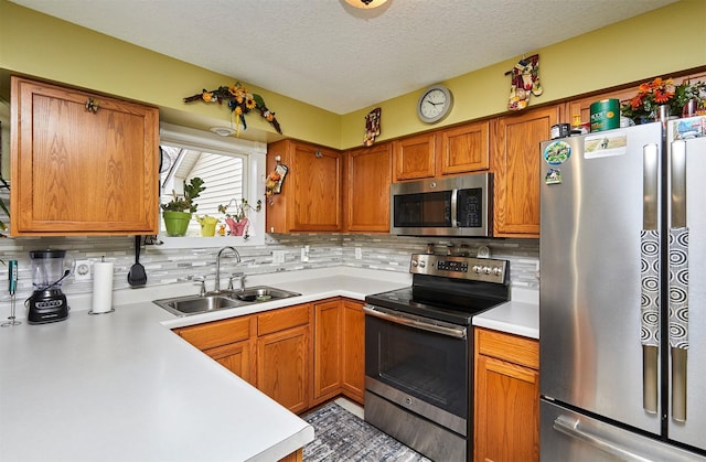 kitchen with backsplash, appliances with stainless steel finishes, light countertops, and a sink