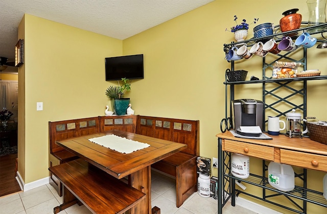 dining area with tile patterned floors, a textured ceiling, and baseboards