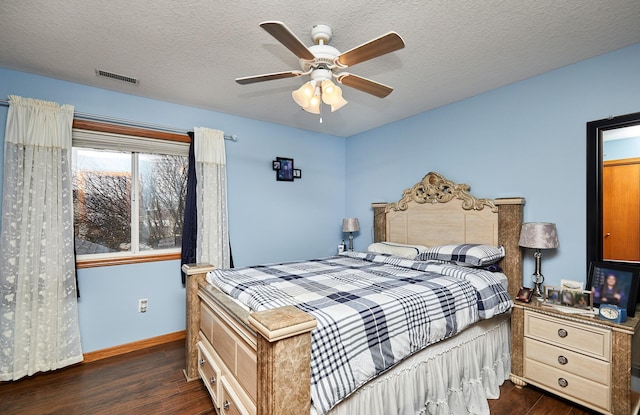 bedroom with visible vents, baseboards, a textured ceiling, a ceiling fan, and dark wood-style flooring