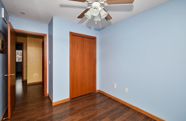 unfurnished bedroom with a ceiling fan, baseboards, dark wood-style flooring, a closet, and a textured ceiling