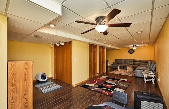 living room featuring ceiling fan, a paneled ceiling, baseboards, and wood finished floors