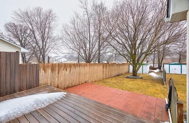 wooden deck featuring a storage unit, a fenced backyard, a lawn, and an outdoor structure