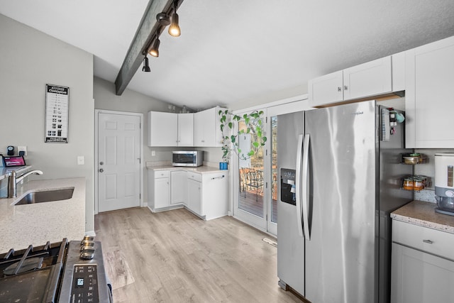 kitchen with vaulted ceiling with beams, a sink, stainless steel appliances, white cabinetry, and light wood-type flooring