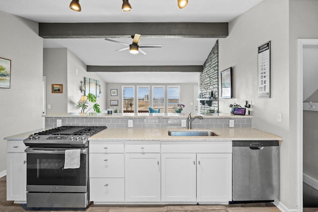 kitchen with beamed ceiling, appliances with stainless steel finishes, white cabinetry, and a sink