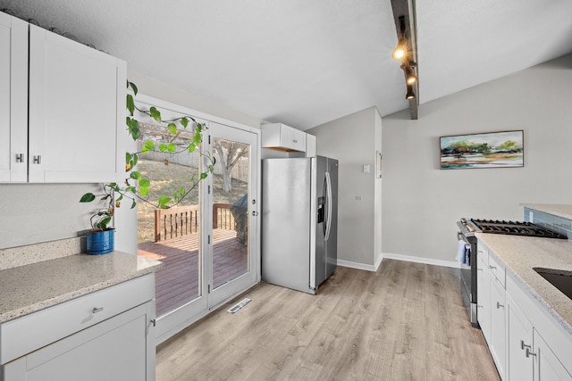 kitchen featuring light stone counters, lofted ceiling, light wood-style flooring, stainless steel appliances, and white cabinetry