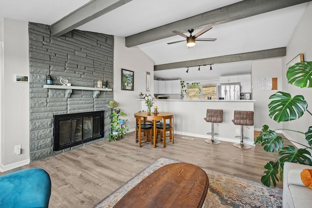 living room with wood finished floors, baseboards, lofted ceiling with beams, a fireplace, and ceiling fan