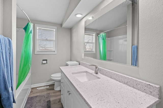 full bathroom with a wealth of natural light, toilet, baseboards, and wood finished floors