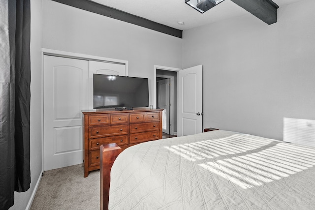 bedroom featuring beam ceiling, light carpet, and a closet