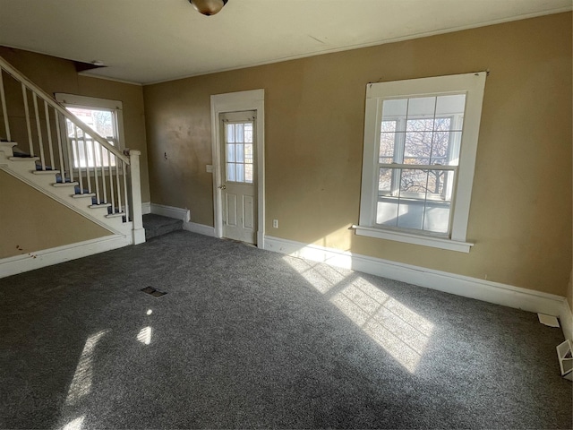 unfurnished living room with carpet, visible vents, baseboards, ornamental molding, and stairs