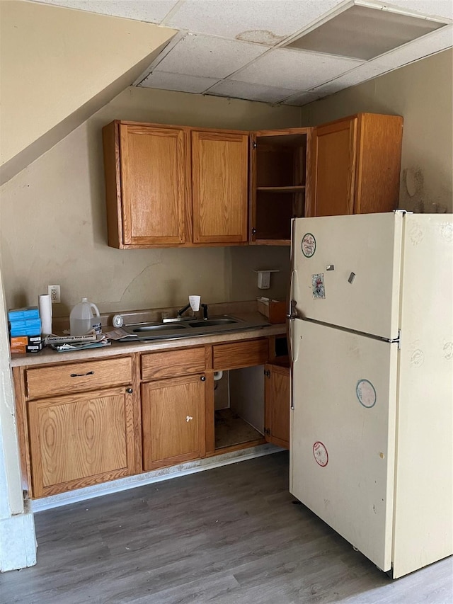 kitchen with a drop ceiling, freestanding refrigerator, wood finished floors, brown cabinetry, and open shelves