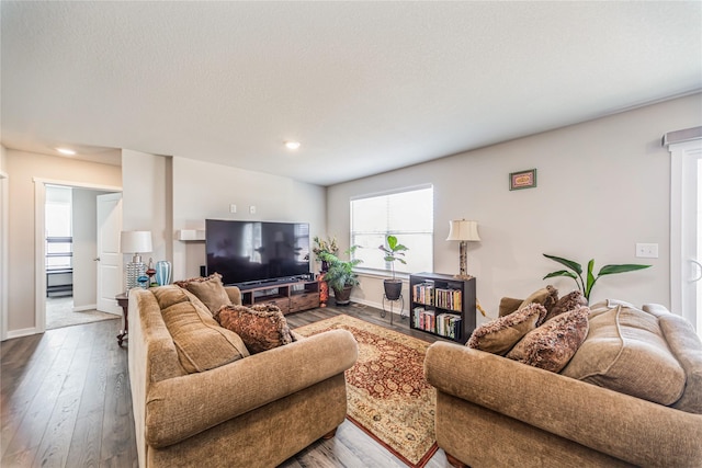 living room featuring recessed lighting, baseboards, wood-type flooring, and a textured ceiling