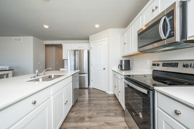 kitchen featuring visible vents, a sink, dark wood-style floors, appliances with stainless steel finishes, and white cabinets