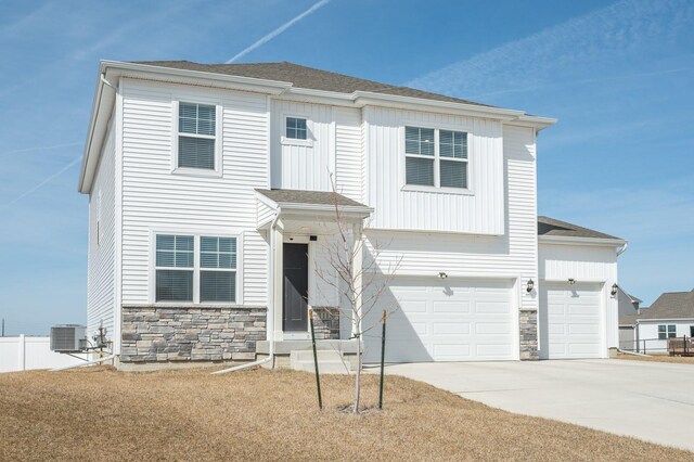 view of front facade featuring central AC unit, driveway, an attached garage, a shingled roof, and stone siding