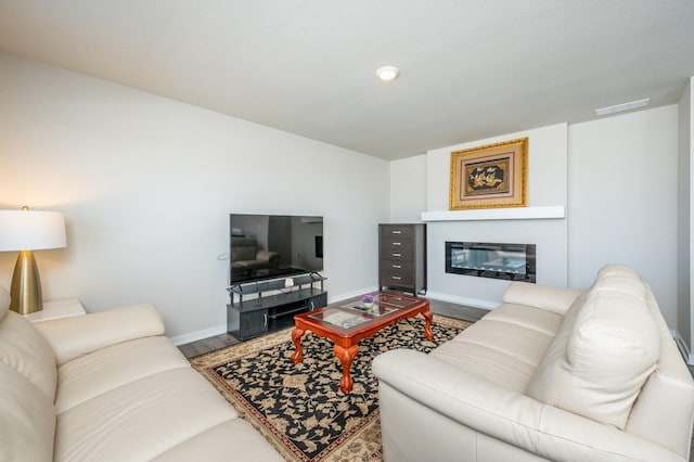 living area with baseboards, wood finished floors, visible vents, and a glass covered fireplace