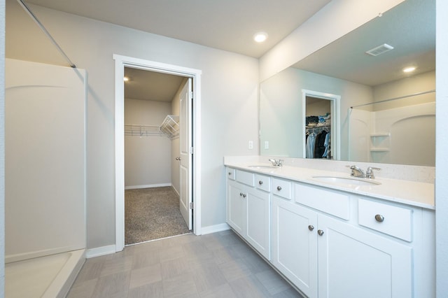 full bathroom with visible vents, baseboards, walk in shower, and a sink